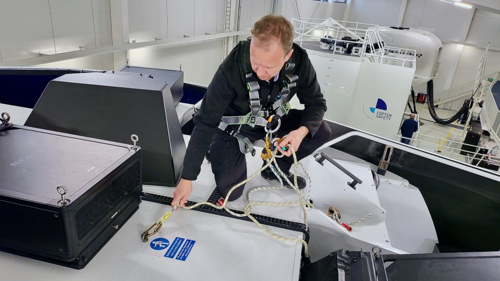 Photo of a maintenance team member practicing the proper safety attachments with the rope and clips. 